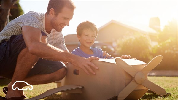 A man who helps his child fix a dummy airplane with smiles on their faces